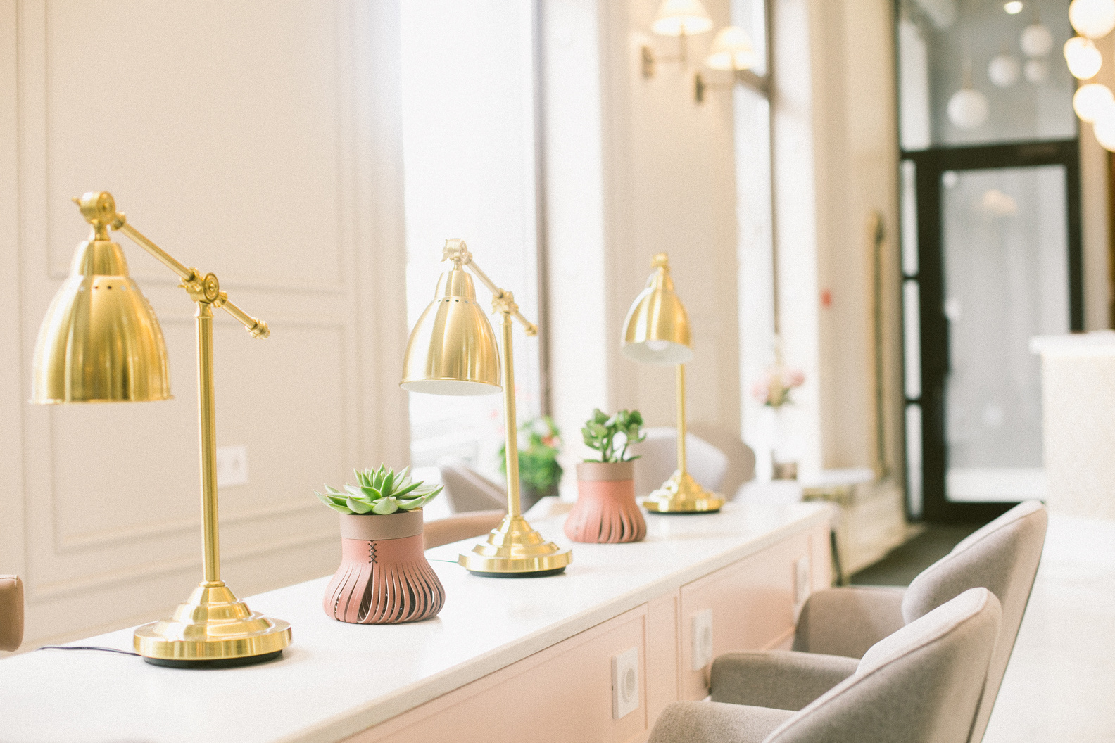 Comfortable chairs and desk with lamps and plant pots in beauty room